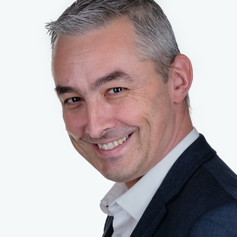 LinkedIn profile picture of Neil, he is wearing a shirt and jacket and is smiling to the camera, at the side.