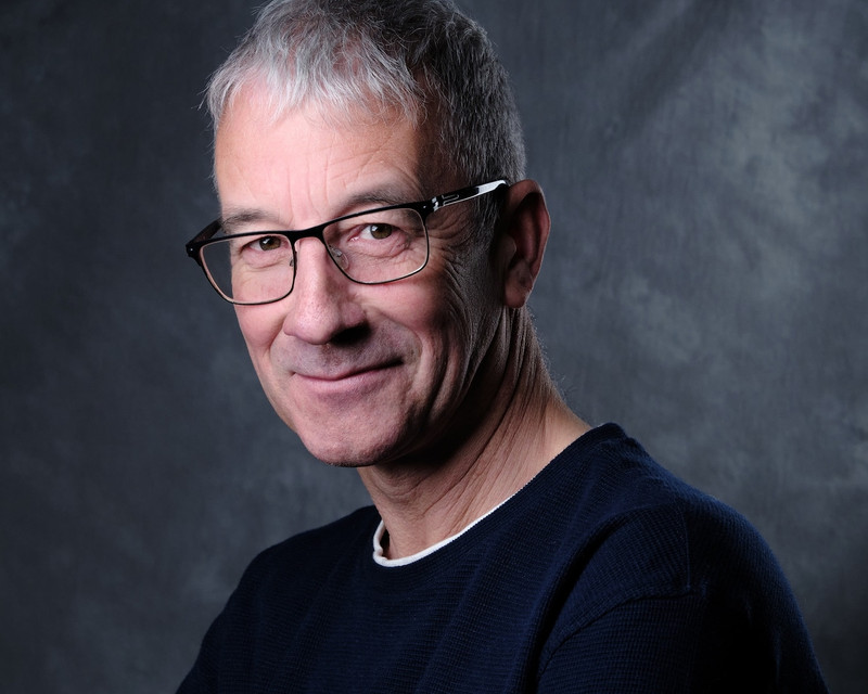 Almost with a laugh, a man with light hair and glasses looks to the camera.