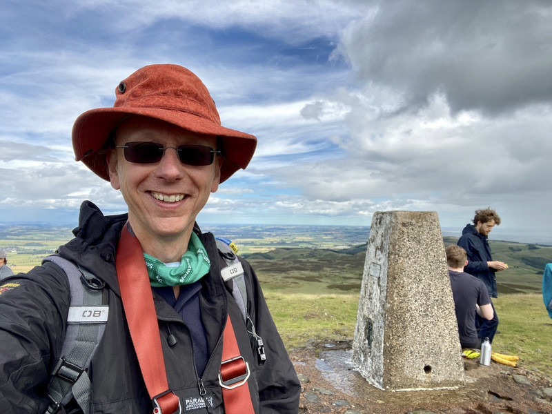 A casual selfie of Richard. He's wearing his walking gear and is at the top of a hill.