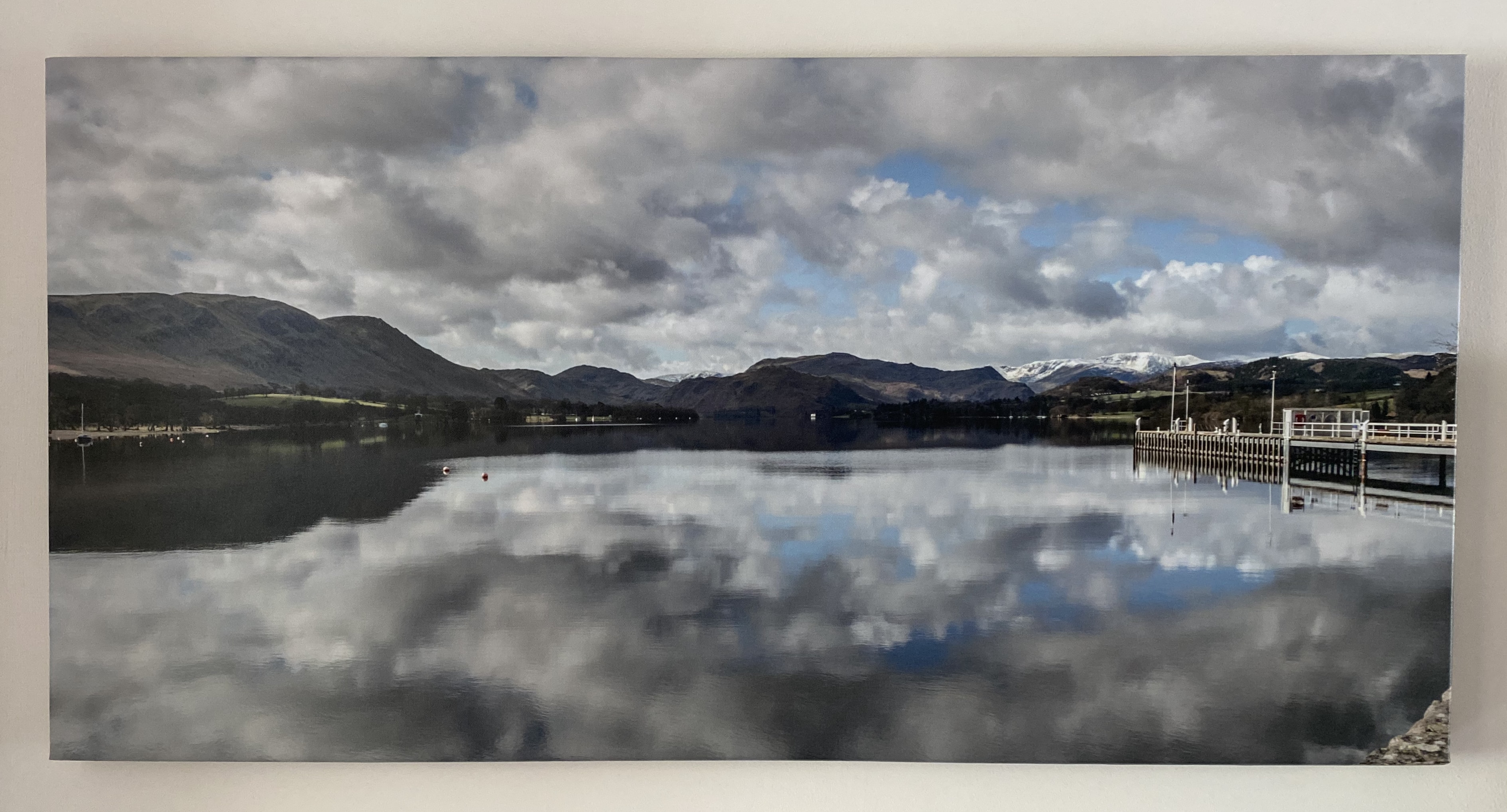 A panoramic canvas showing a lake and pier, with mountains in the distance.