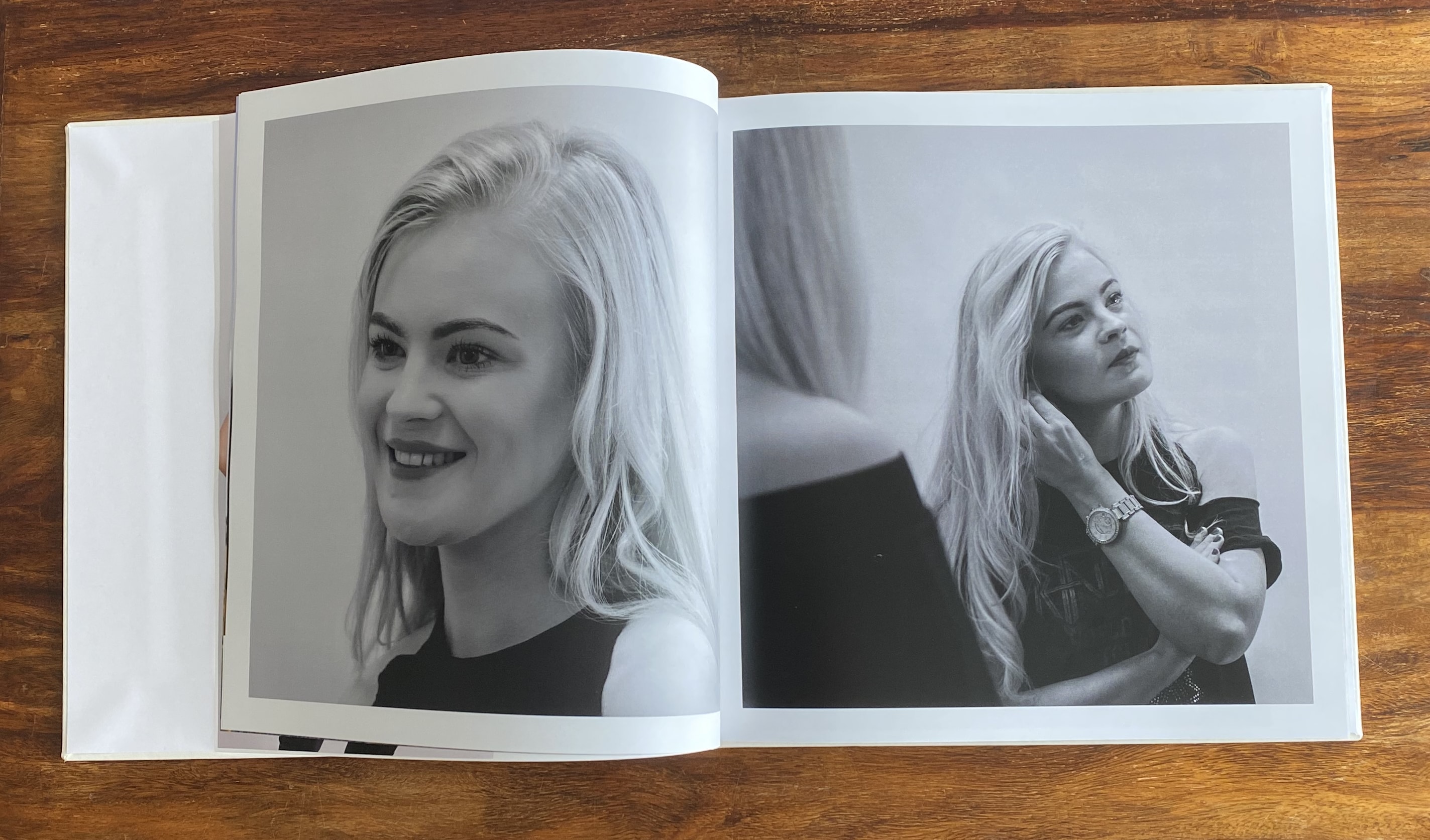 A photo book opened to a centre page, with a photo of a young woman smiling on one page and putting earrings in on the other.