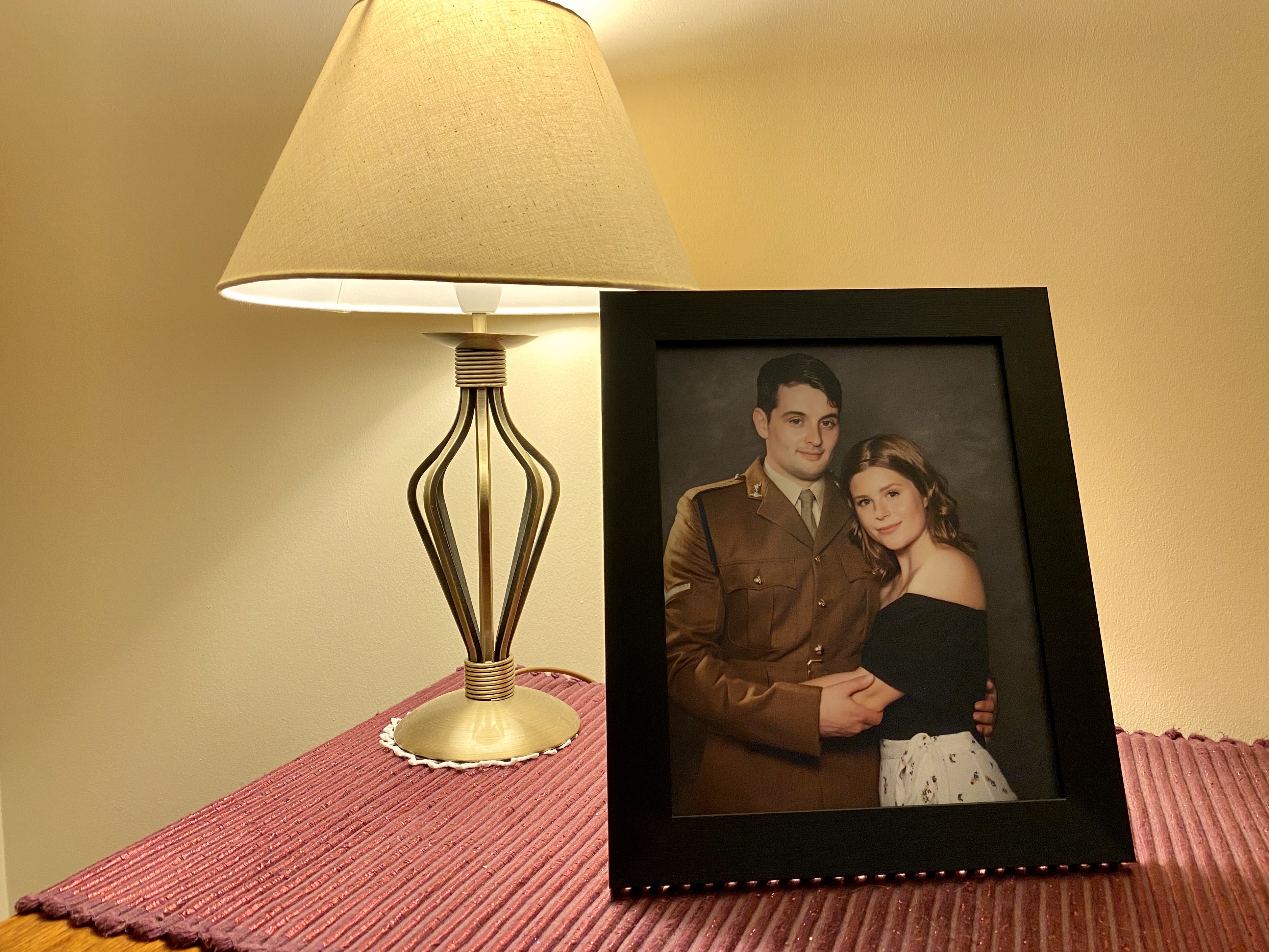 A framed image of a young man in army uniform, with a young woman next to him. They have their arms round each other and they look to the camera.